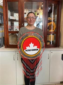 Janice Johnstone, an artist from the Muskeg Lake Cree Nation, holding a Petro-Canada logo made with traditional Indigenous beadwork techniques