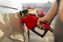 Main tenant une buse de carburant à une pompe à essence et remplissant leur voiture