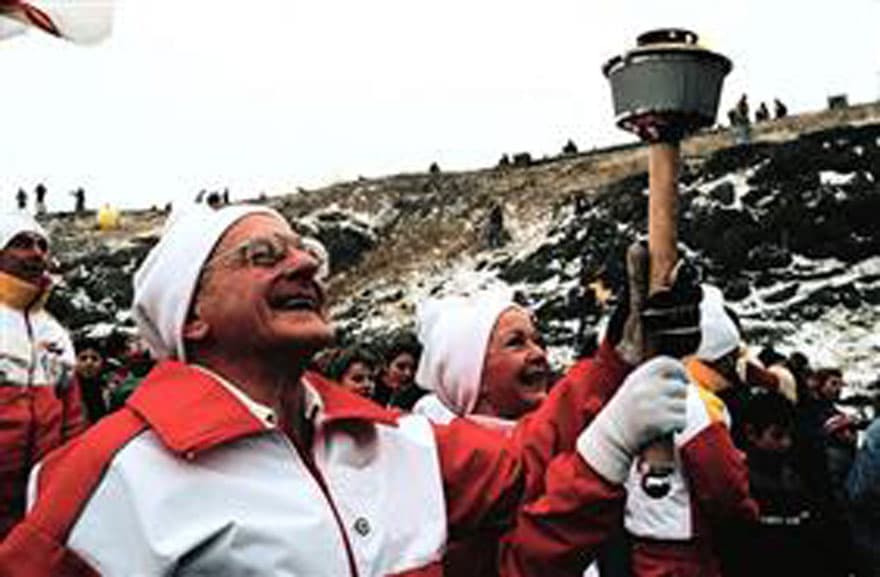A man wearing Canadian colours and carrying the Olympic torch through Calgary